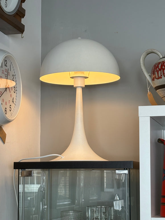 White Panthella style lamp, switched on against a grey wall
