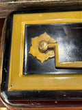 Close-up detail of brass knob handle and decorative brass mount on the black lacquered lid of the Henry Loveridge Victorian cash box