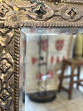 Bevelled mirror set within brass repoussé coat rack, close view