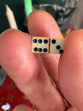 Miniature bone domino tile held between fingers showing pip detail