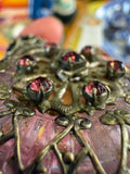 Close-up macro detail of claw-set pink rhinestones in silver filigree on Czech perfume bottle