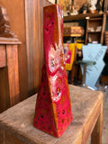 West German Fat Lava vase on a wooden bench, showing full triangular form and volcanic glaze texture.