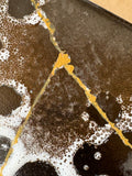 	Macro detail of gold repair line crossing brown and white glaze