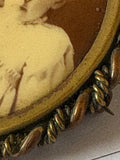 Edge detail of Victorian tintype brooch in gilded brass frame.