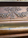Close-up of embossed fruit swag, ribbon bow and crossed trumpets on a 1920s Crawford's biscuit tin