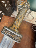 Overhead view of the sword’s lion-head pommel and cross-guard, held to show the carved mane detail and laurel-decorated guard.