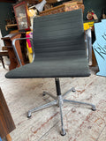 Eames EA108 chair, front view, showing black ribbed fabric seat and back with chrome armrests.