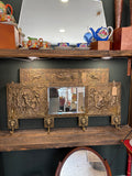 Brass repoussé coat rack with bevelled mirror displayed on a wooden shelf unit