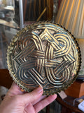 Hand holding an Arts and Crafts brass dish showing the raised Celtic knot and pie crust edge