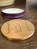 Medallion resting beside its open fitted box on wooden surface