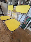 Pair of vintage Formica dining chairs viewed from above, showing yellow seat pattern and chrome legs.