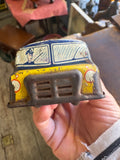 Close-up of front end of GTP Motorways tinplate coach held in hand showing yellow fascia, printed driver figure in windscreen, headlight circles and pressed metal grille