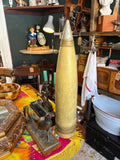 “Large 59cm Soviet-era artillery shell display replica standing upright on antique shop table, olive green body with grey metal-effect nose”