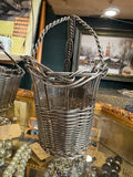 Woven wire wine basket from the narrow end, showing twisted rope handle and braided rim