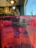 Close-up of the official Dartington Crystal black label on the cranberry glass vase, confirming maker and brand authenticity.