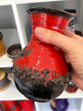 Hand holding vintage red and black fat lava vase to show scale