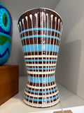 Close-up of white drip glaze running over brown and blue striped vase