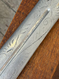 Close-up of the sword blade’s etched floral and scroll decoration along the fuller.