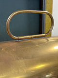 Close-up of hinged oval brass carry handle on domed hood