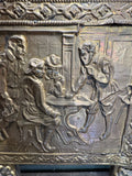 Detail of brass repoussé tavern scene showing figures seated at a table