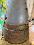 Close-up of base and driving band area of Soviet artillery shell replica showing painted brass-effect cartridge case and body join