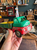 Hand holding vintage Wells-Brimtoy 1950s tinplate flatbed truck showing three-quarter front view