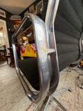 Close-up of Eames EA108 chair's side frame and armrest, showing chrome detail and black fabric.