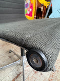 Close-up of Eames EA108 chair's seat corner showing black fabric texture and swivel mechanism.