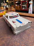 Three-quarter front view of vintage 1960s Japanese tinplate ambulance toy car in white red and blue lithography