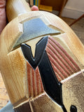 Close-up of Art Deco figure's hat and face detail on ceramic bottle.