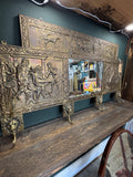 Side view of antique brass coat rack showing embossed tavern scene panels