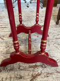 Close-up of the base structure of the Chinoiserie side table showing the H-stretcher rail, central turned spindle connector, red painted curved bracket feet, and gold banding on the turned leg sections.