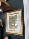 Framed hand-coloured child portrait displayed on dark green wall