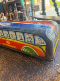 Low angle side view of GTP Motorways tinplate coach showing full length of blue roof, passenger window illustrations and GTP Motorways lettering on red and yellow body