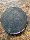 Reverse of the medallion showing plain dark surface