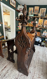 Side view of an antique Gothic Revival oak lectern showing carved finials, scrolled brackets, and pierced tracery side panels