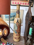 Tall ceramic Cinzano advertising bottle with textured sand-and-ochre glaze, zebra and bottle motif, displayed on a side table.
