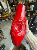Red drip glaze pottery vase held up against shop shelving