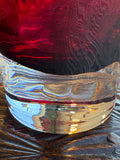 Detail of the base of the Dartington Crystal cranberry vase showing the transition from deep ruby glass to a clear crystal foot, with light refracting through the thick glass in rainbow tones.​​​​​​​​​​​​​​​​