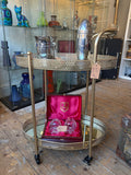 Gold oval drinks trolley with mirrored shelves and castors