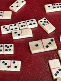 Close-up of scattered miniature bone domino tiles on red surface