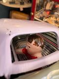 Close-up of driver figure visible through car window 