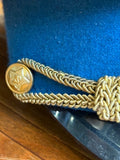 Close-up of gilt braided officer's chin cords and a star button on the sky-blue band of a Soviet cap