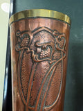 Close-up of Art Nouveau copper vase showing embossed foliate and grape motif near the rim