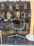 Eames Aluminium Group EA108 chair in shop window, side view with London street visible through glass.