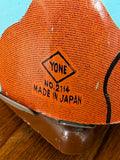 Close-up of Yone maker's mark, "No.2114, Made in Japan," stamped on tin dog toy.