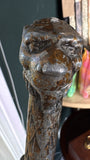 Extreme close-up of the lion-head pommel, showing the worn silver and gold paint finish over the cast metal surface.