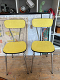 Pair of vintage yellow Formica dining chairs, straight-on front view showing matching set.