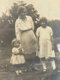 Close-up of original 1930s photograph showing mother and two daughters in a garden