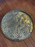 Overhead view of a 16.5cm brass dish with a hand-worked Celtic interlace knot on a punched ground
